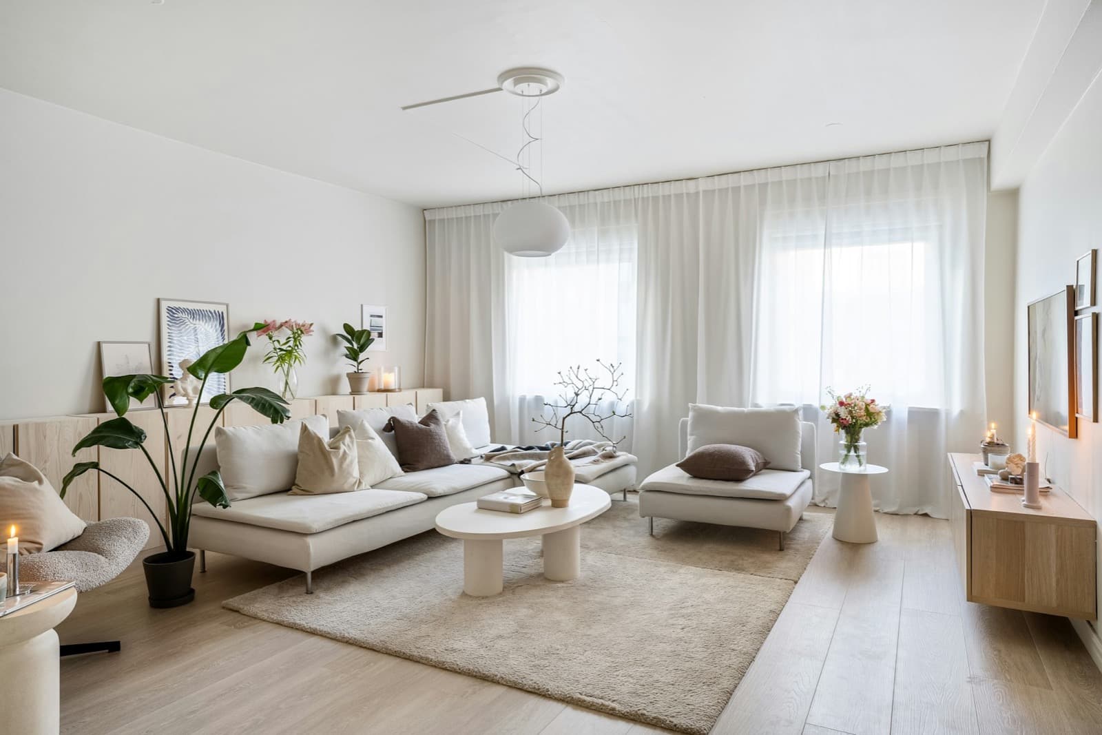 A bright living room with a cream sofa, a round coffee table and sheer curtains
