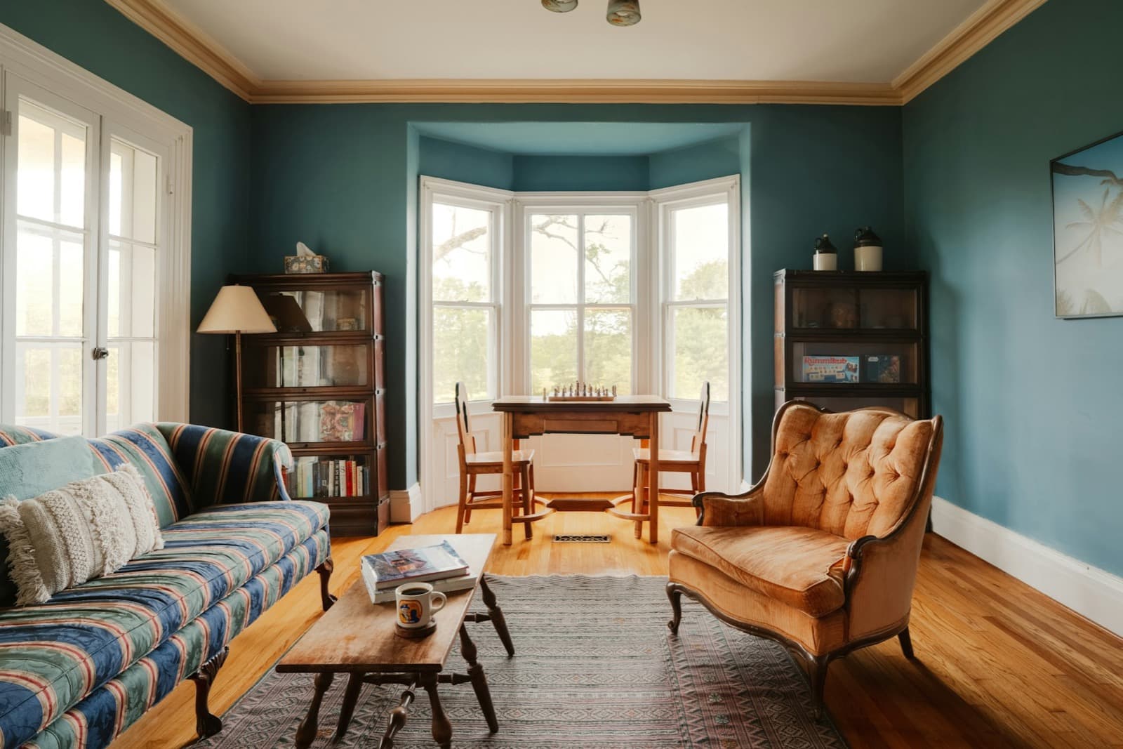 Teal-painted sitting room with a bay window in a period flat